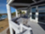 Spacious waterfront balcony with grey decking and white railings.