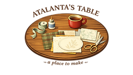 Atalanta's Table logo with walnut craft table illustration and handmade paper elements