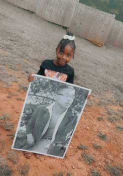 Grieving child holding poster of deceased father