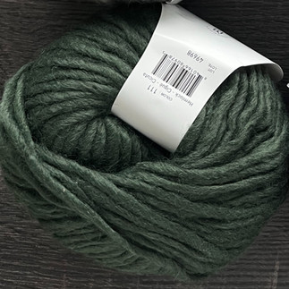 a deep forest green colored super bulky yarn with the look of a bit of a rustic texture to it