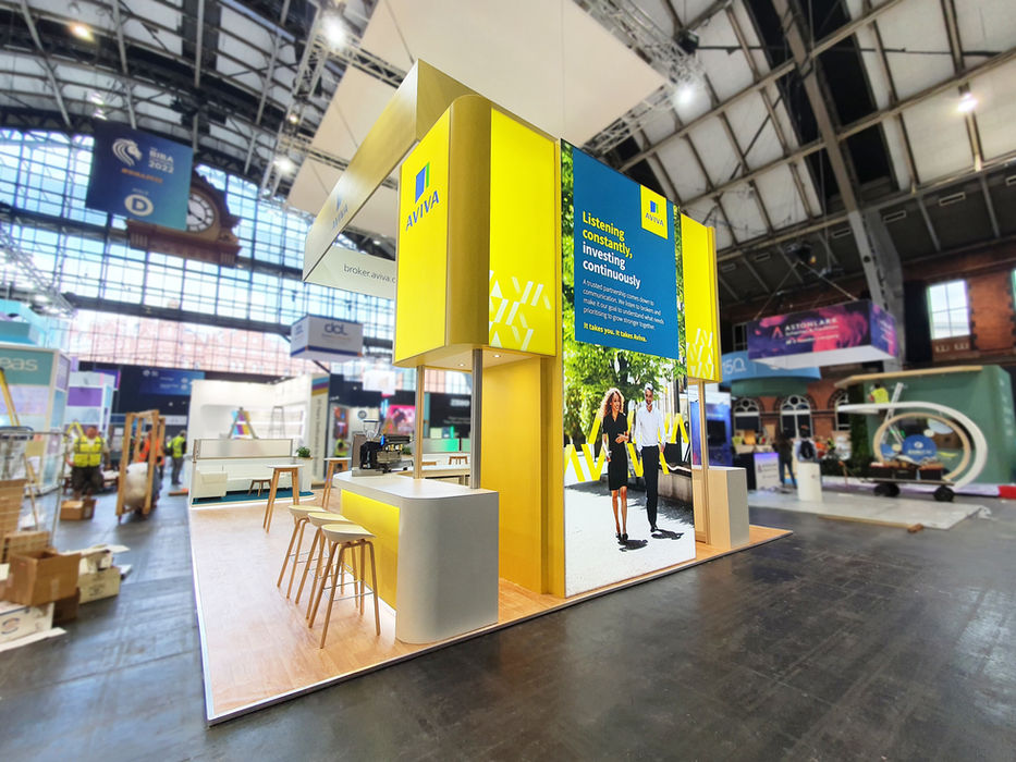 Custom exhibition stand for Aviva at BIBA 2022, featuring branded graphics, coffee bar, and a meeting space.