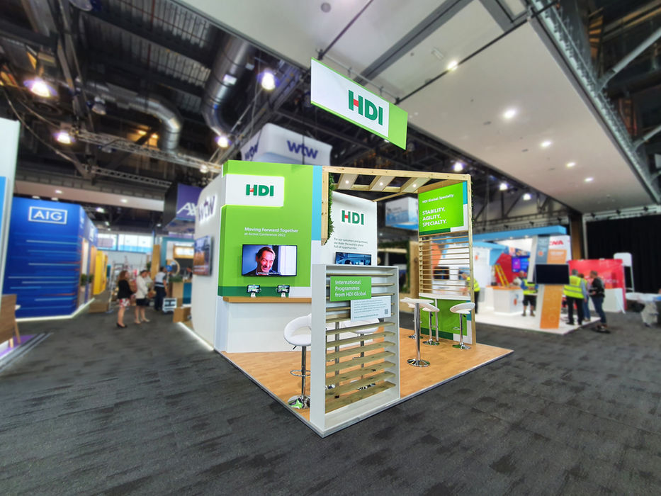 Custom sustainable exhibition stand for HDI Global at Airmic 2022. The reusable exhibition stand features a digital display, biophilic design, slat walls and branded graphics.