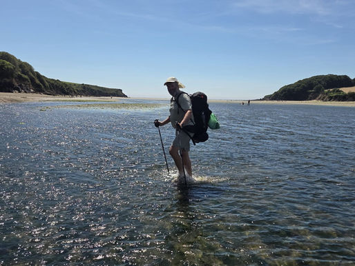 Man die estuarium oversteekt met wandelstokken en rugzak