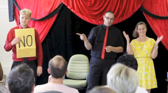 magicians perform stage magic for a women in a yellow dress at a tea building event