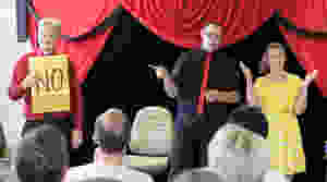 magicians perform stage magic for a women in a yellow dress at a tea building event