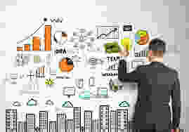 Man in black suit writing down plans on a white board