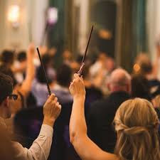 2 people waving harry potter wands to the sky at a convention