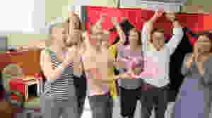 a group of people cheering with a balloon model done at a team building event