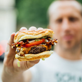 Will and Pops Cheeseburger being held up to the counter by a man out of focus in the background