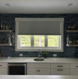 Kitchen with a single cellular shade covering three casement windows.  Shade lowered half way.