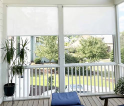 Light beige solar shades in the mid-way down position on a back porch.
