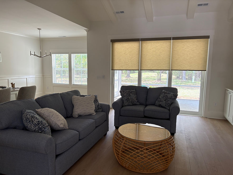 A cozy sunroom, bathed in natural light filtering through light-filtering roller shades, creating a serene and inviting atmosphere in Sunset Beach, NC.