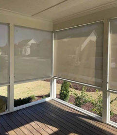 Tan solar shades in the fully down position on a back porch.