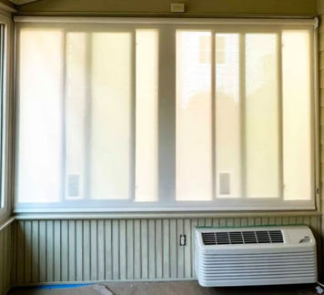 Sunroom with one roller shade in semi-transparent fabric covering a pair of sliding windows.  Shades lowered.