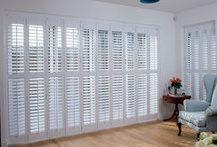 2 1/2" bi-fold wood shutters with tilt-rods and center rails installed over a sliding glass door in a painted finish.  Inside mount.  