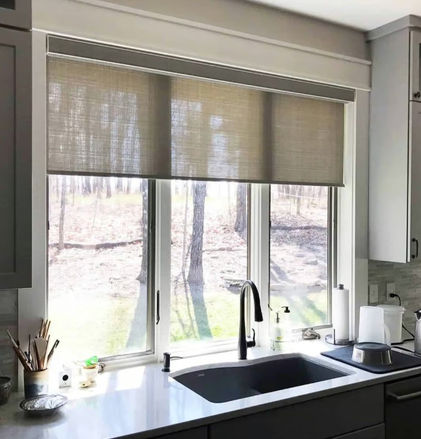 Kitchen with one inside mounted roller shade in synthetic seagrass covering three casement windows.