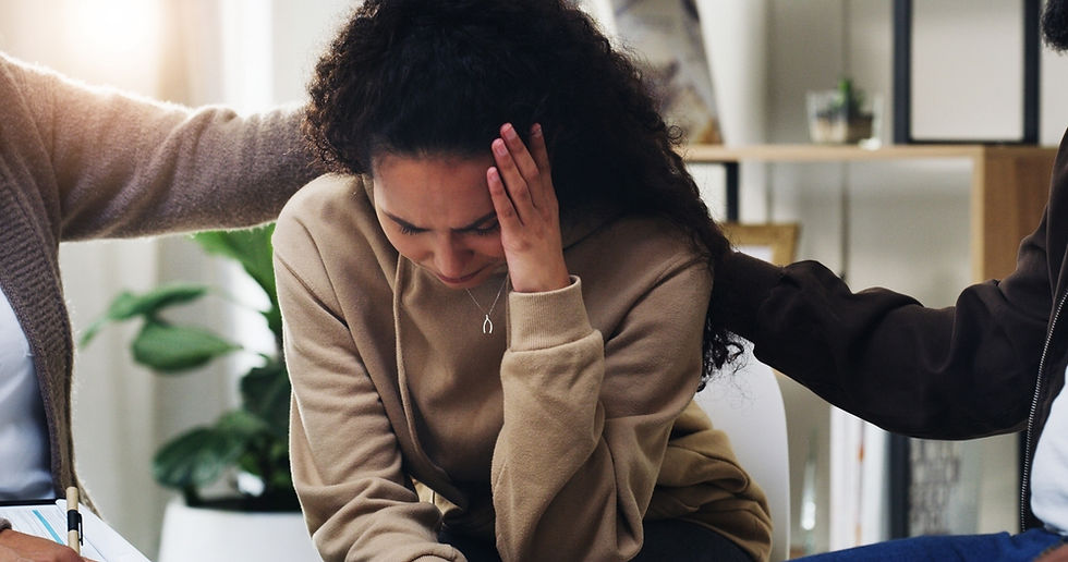 A woman sits in distress from her trauma while two people attempt to comfort her