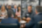 Two images: Left shows a panel of four smiling people in a meeting room. Right shows two men talking in an industrial setting, one smiling.