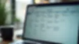 Laptop screen displaying a digital calendar with events listed for multiple days. A coffee mug is on the table; soft, blurred background.