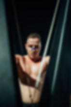 Young blonde man competing in a hybrid fitness challenge at night, shirtless, showing inte