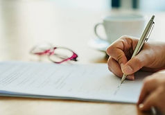 person holding a pen writing on paper