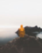 Kuvituskuva: Henkilö keltaisessa takissa katsoo kalliolta merelle. - kuva unsplash.com