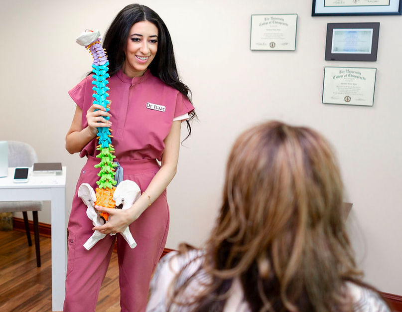 Nashville-chiropractor-Doctor-Christine-Isaac-holding-a-spinal-collumn-model-explaining-to-a-patient-the-causes-and-side-effects-of-spine-misalignment
