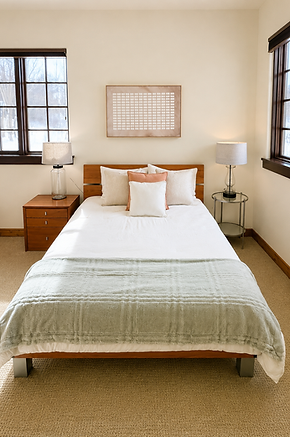 Staged bedroom with a wood platform bed, sage green quilt, and matching nightstands with lamps