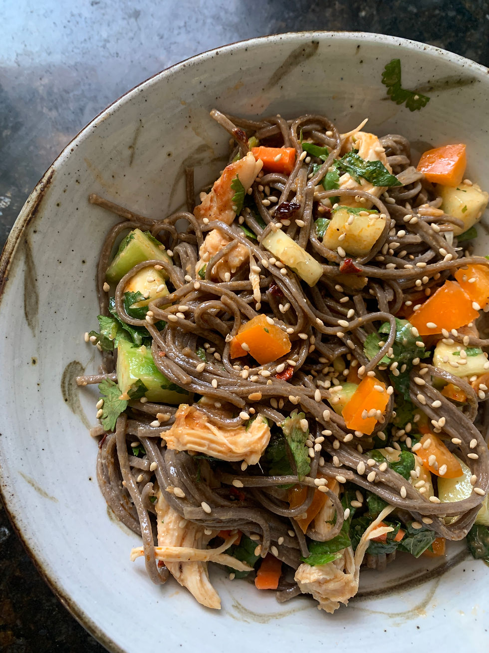 close-up of pretty earthy ceramic shallow bowl with spicy sesame noodles