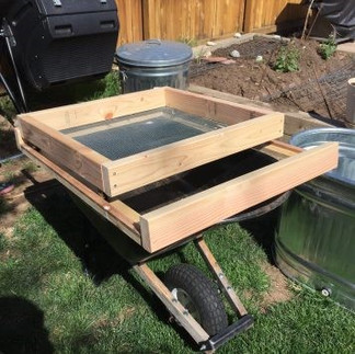 wooden compost filter on top of wheelbarrow in garden