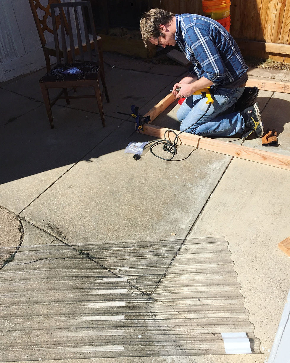 Man constructs cold frame outside.