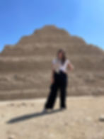 A woman stands in front of the step pyramid