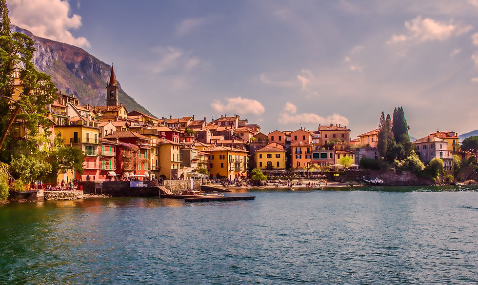 Water and rustic, Italian style buildings along the shore with a mountain in the distances