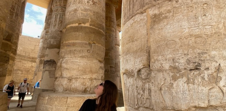 A woman looks up at the pillars inside the Temple of Karnak