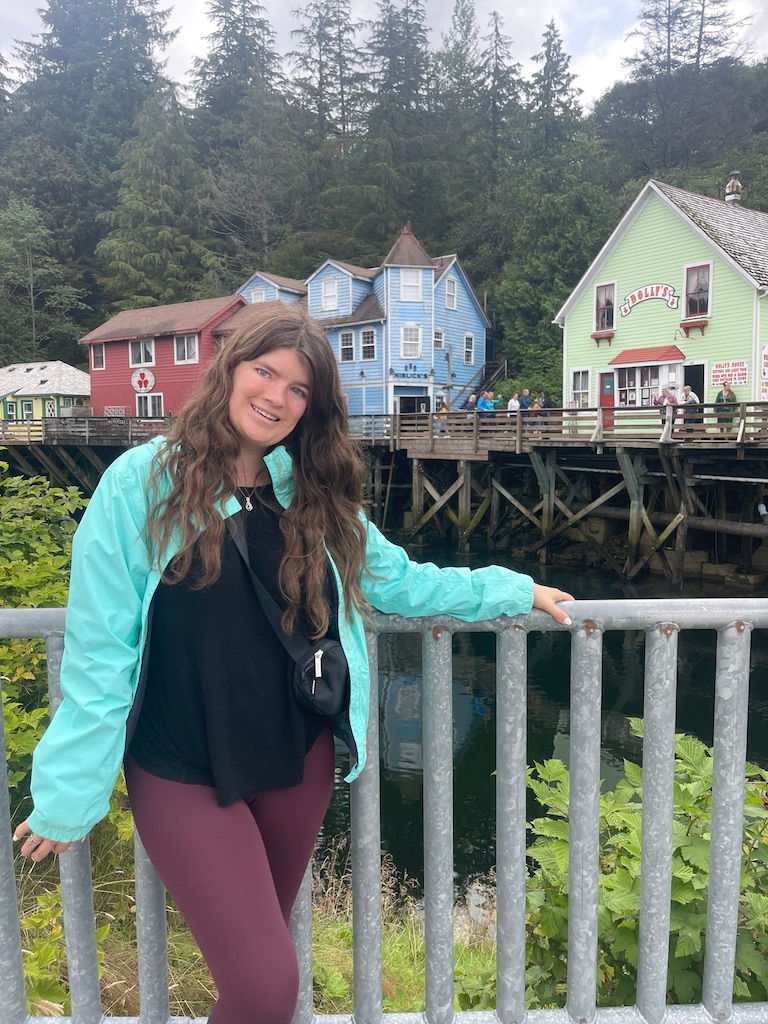 A woman wearing a rain coat in front of colorful buildings in Alaska