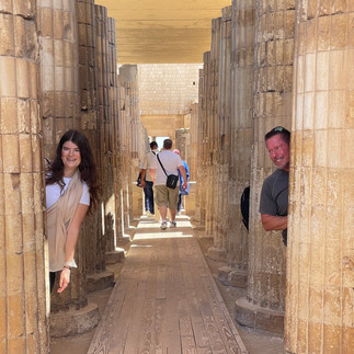 A man and a woman peak out from behind pillars in the Saqqara Temple