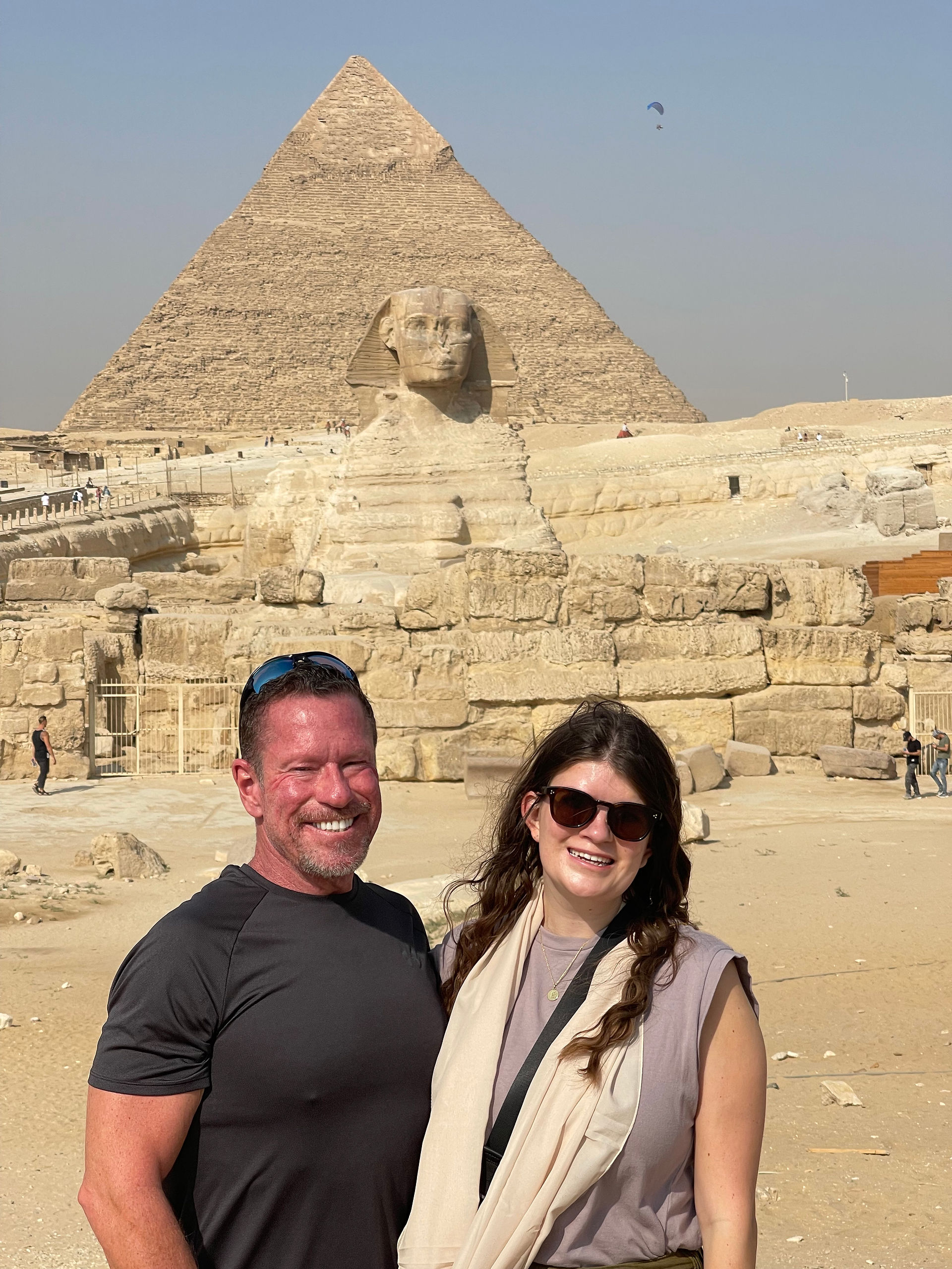 Man and woman stand in front of the Great Sphinx and the Pyramids in Egypt