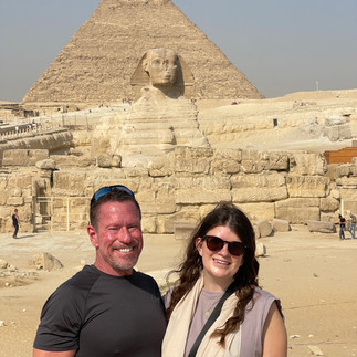 Man and woman stand in front of the Great Sphinx and the Pyramids in Egypt