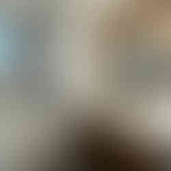 Bathroom vanity with white counters, oak cabinets and circular brass mirror.