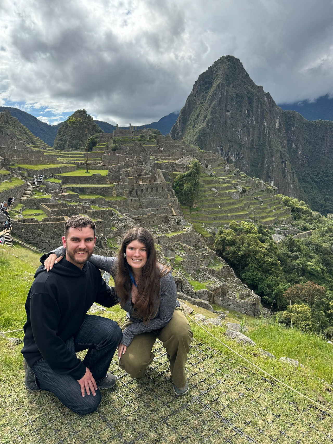Man and woman crouched in front of Machu Picchu