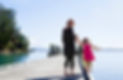 A grandmother is walking along a pier with her young grandchildren, safe in the knowledge that she has good retirement investments from the Smart Advice Collective, NZ