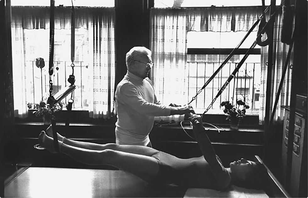 Joseph Pilates instructing a woman on a Cadillac machine