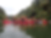Group of Howick College students in red canoes raising paddles, cheering on river.