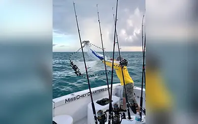 Guest working a fishing rod aboard Miss Chief during a Key Largo offshore charter.