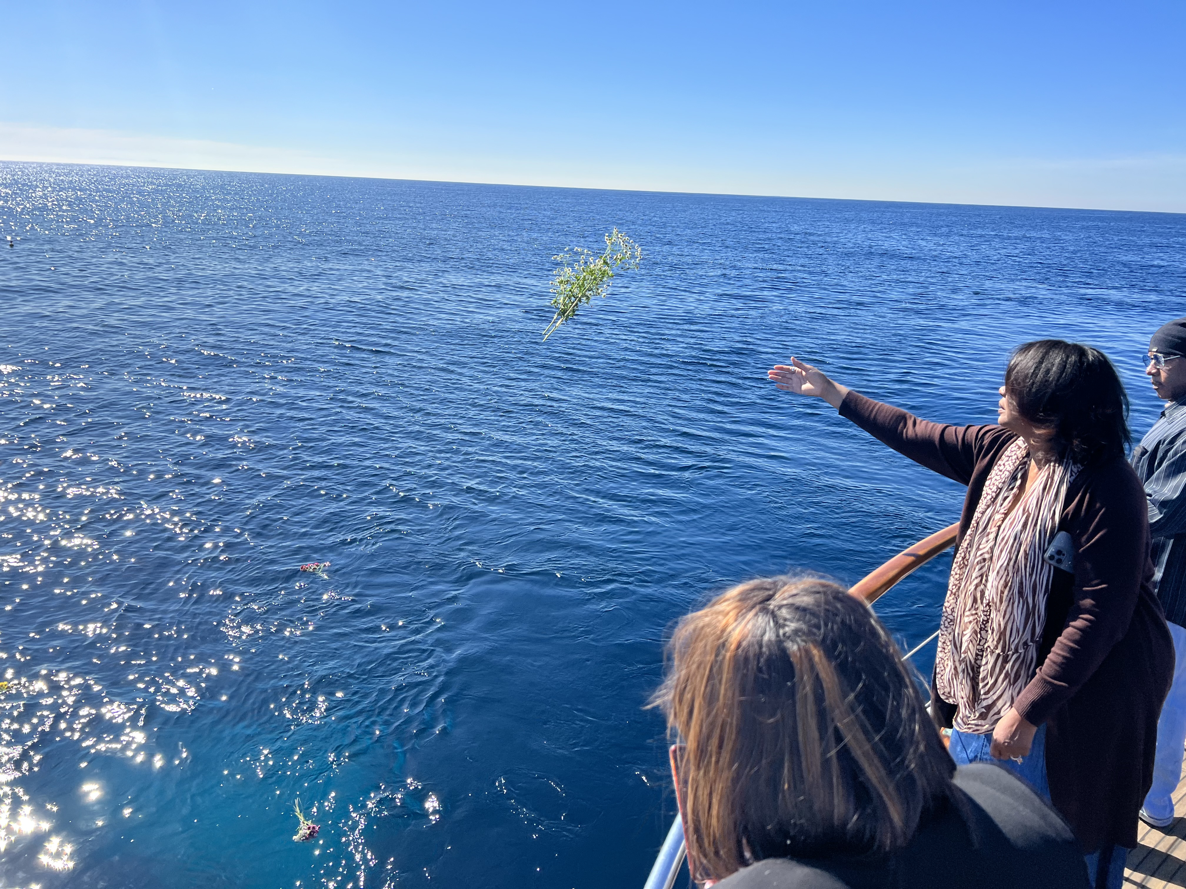 A mourner gently tossing a floral bouquet into the Pacific Ocean during an ash scattering ceremony off the California coast