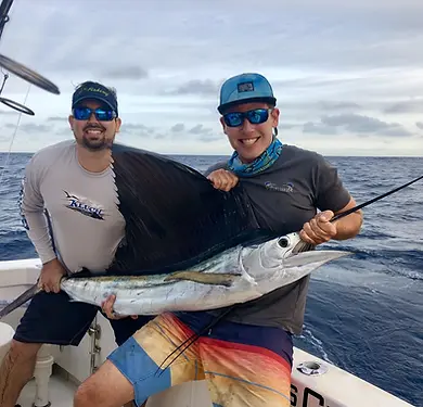 Two anglers holding a sailfish aboard Miss Chief on a private offshore charter from Key Largo.