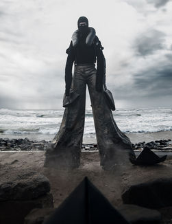 model wears a long black dress walking on the beach