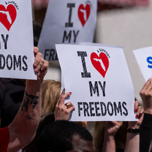 An image of people holding signs that say "I heart my freedoms" (where the heart has the state of Florida in it) and a sign that says "support parents' rights."