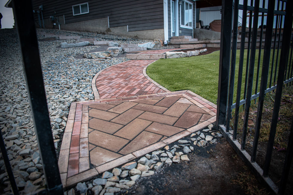 Curved brick walkway with herringbone pattern and clean edging through landscaped yard