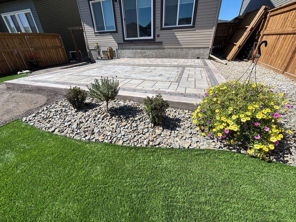 Backyard landscaping with stone patio and garden beds in Cochrane Alberta